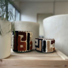 Atelier Marhaban Labyrinthe geurkaars in glazen pot met handgeweven textiel in beige, oranje en bruintinten.