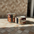 Atelier Marhaban Labyrinthe geurkaars in glazen pot met handgeweven textiel in beige, oranje en bruintinten.